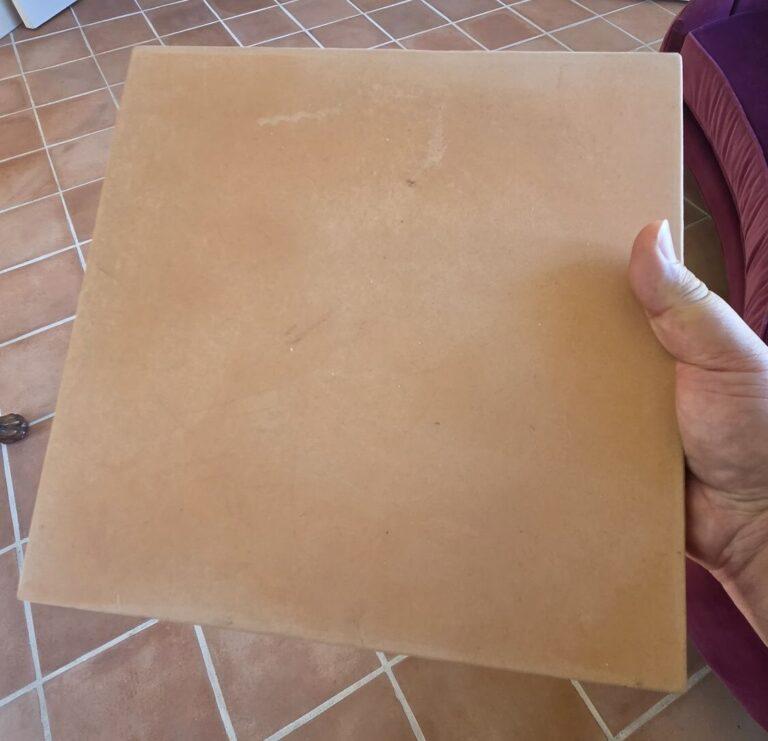 Front of a concrete tile made to look like terracotta, held over a real terracotta floor in Miami Beach