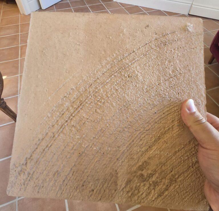 Back of the look-alike tile showing concrete, held over a real terracotta floor in Miami Beach