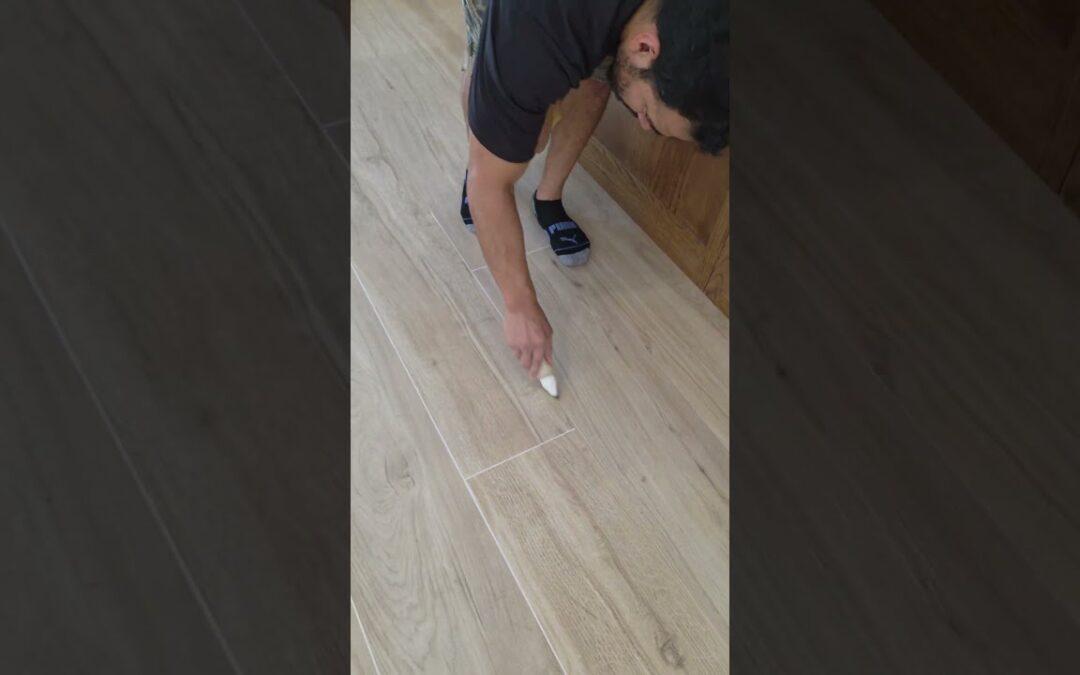 Crew applying grout color sealer to white grout on wood-look tile in a Pinecrest home