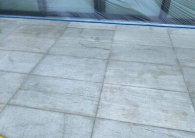 Natural stone patio at a Miami waterfront home before cleaning and sealing, with water marks and uneven staining in front of taped-off sliding doors