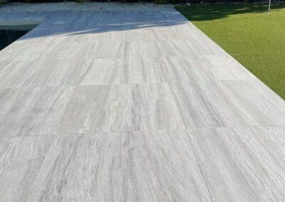 Long run of natural stone pool deck pavers after low-moisture cleaning and penetrating sealer in Miami