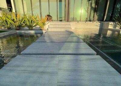 Natural stone stepping stones across a pool after cleaning and sealing at a Miami home